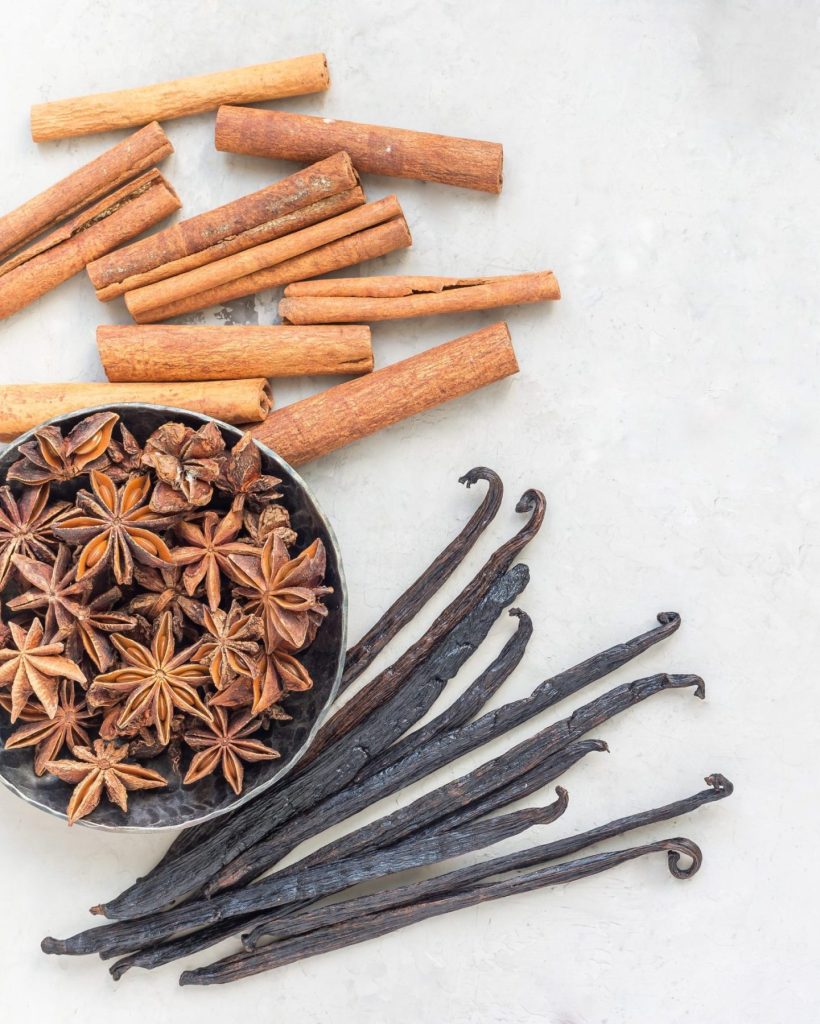 Different kinds of aromatic winter spices on a gray concrete background, top view, square format